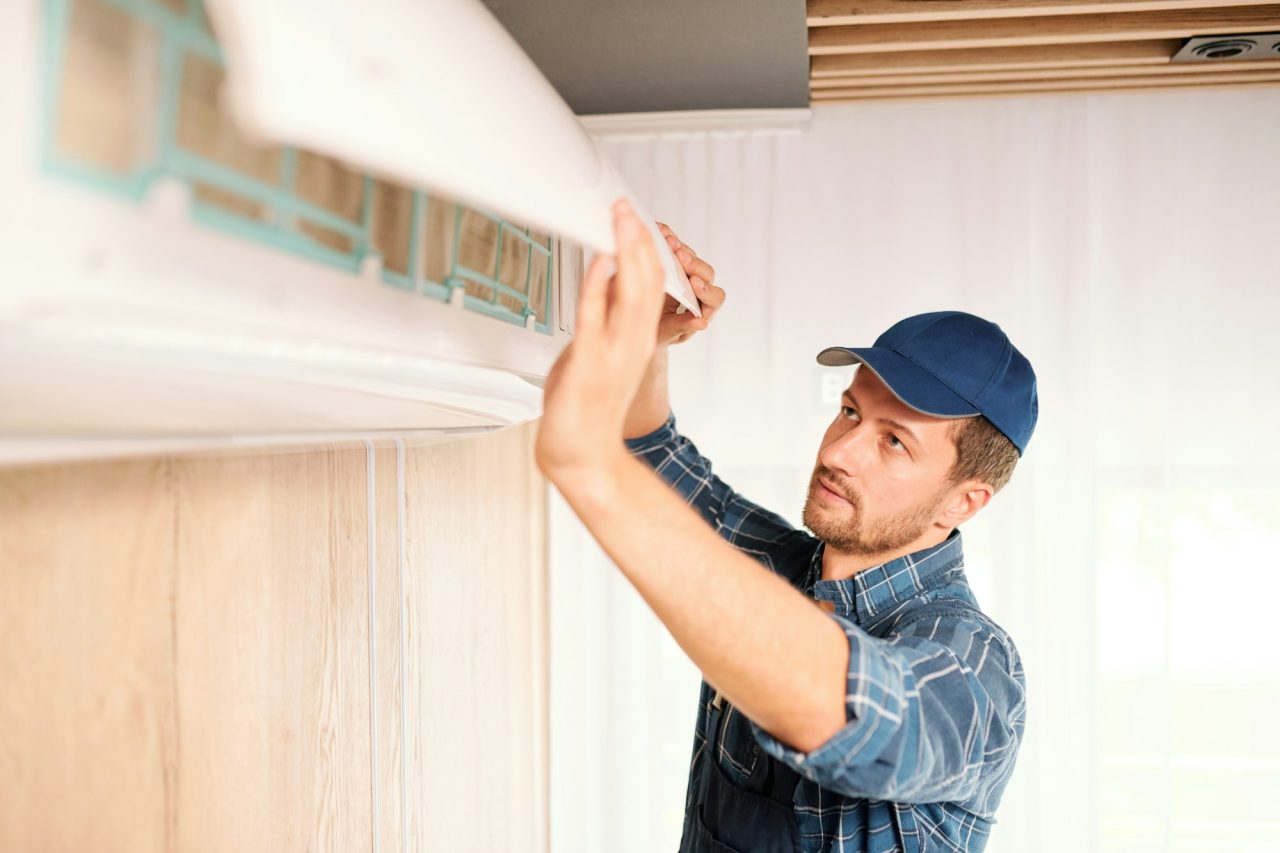 young-electrician-or-repiar-service-technician-opening-lid-of-air-conditioner